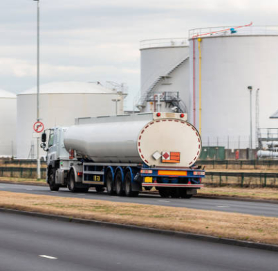 Tanker truck in motion on the road with oil depot in the background
